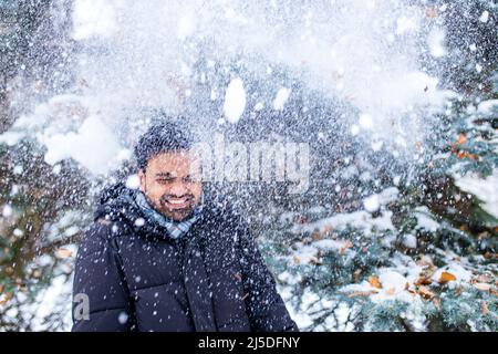 indian man enjoying snowflakes falling from upwards in forest Stock Photo