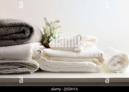 Clean bedding and towels on wooden bench and white isolated background. Clothes cleaning service concept. Front view. Horizontal composition. Stock Photo
