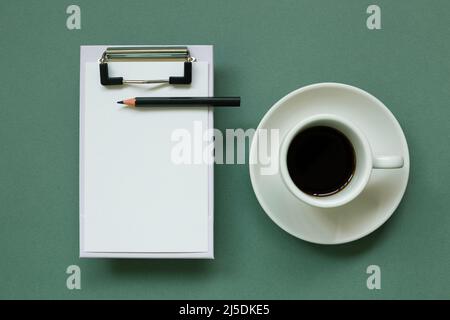Clipboard and paper sheet with cup of coffee on green background. top view, copy space Stock Photo