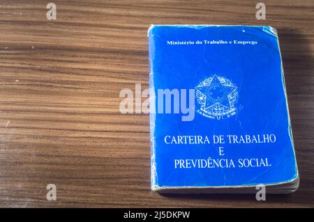 Translation: Federative Republic of Brazil, Ministry of Labor. Work Card (Carteira de trabalho) next to Brazilian real coins, Brazilian money. Stock Photo