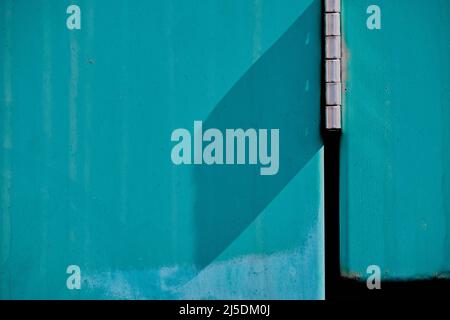 Abstract:  Turquoise metal door with chrome hinge seen in close-up.  Exterior door streaked with vertical lines most likely created by rain. Stock Photo