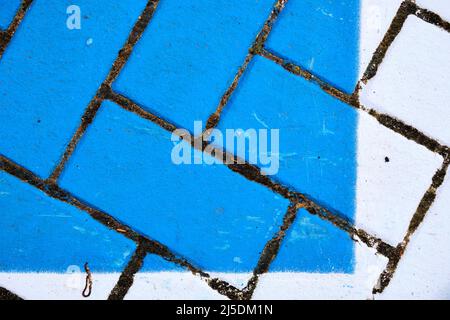 Bricks painted blue and white form herringbone pattern.  Bricks are textured and worn in places. Stock Photo