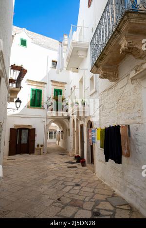 A typical narrow street in Locorotondo often decorated with flower, Apulia, Italy Stock Photo