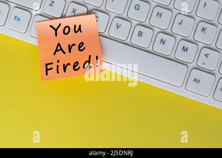 You're Fired text on orange sticky note on top of white keyboard. Human Resource and contract concept. Stock Photo