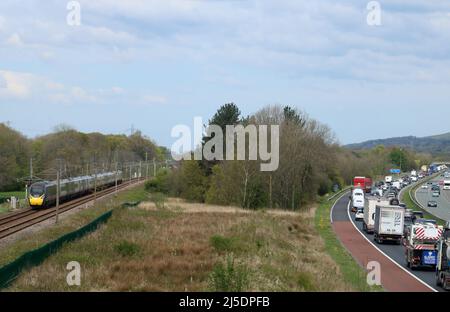 It's quicker by train. A pendolino electric train speeds along the West Coast Main Line railway while traffic on the adjacent M6 is reduced to a crawl. Stock Photo