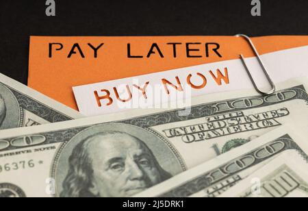 BNPL or Buy Now Pay Later concept. Dollar bills and label with message on black background Stock Photo