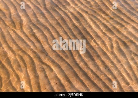 Sandy seabed with wavy relief pattern under shallow water, abstract natural background photo texture Stock Photo
