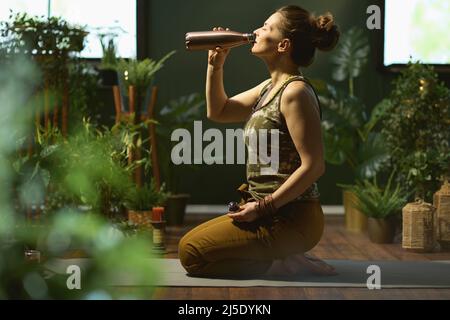 stylish housewife with bottle of water in the modern green house. Stock Photo