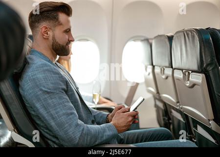Bearded man using mobile phone in airplane Stock Photo