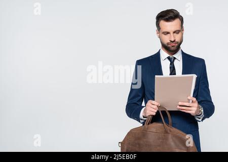 economist with leather briefcase looking at folder with documents isolated on grey Stock Photo