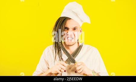 Male cook in white uniform sharpening crossed knives. Concept of preparing to make food. Stock Photo