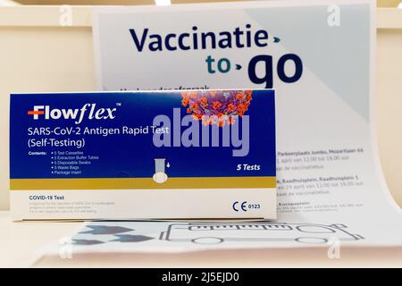 A retail box of Flowflex Covid-19 antigen Rapid test  kit  displays in front of a information leaflet in Dutch "Vaccinatie to go" , Netherlands Stock Photo