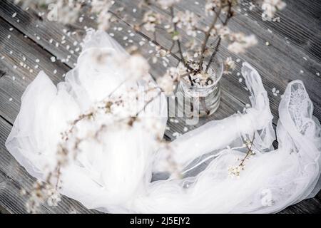 White cherry flowers twigs on glass vase on wooden table on spring time Stock Photo