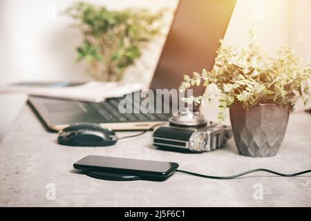 Charging the smartphone with wireless charger on desktop. Stock Photo