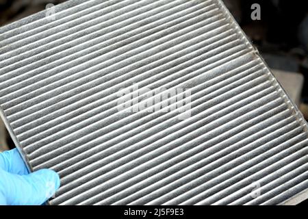 A closeup of an old dirty used car AC air conditioning filter full of dust removed from the vehicle to be replaced with a new one, cabin air carbon fi Stock Photo