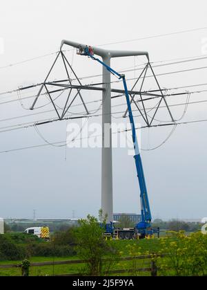 Bridgwater, Somerset, UK.  23rd April 2022.  Workmen on an aerial platform working on one of the new National Grid T-Pylons at Bridgwater in Somerset which have been built across the Somerset levels as part of the Hinkley Point C.  Picture Credit: Graham Hunt/Alamy Live News Stock Photo