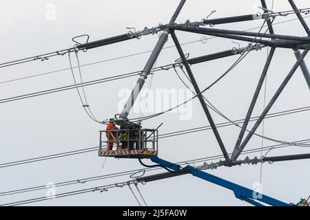 Bridgwater, Somerset, UK.  23rd April 2022.  Workmen on an aerial platform working on one of the new National Grid T-Pylons at Bridgwater in Somerset which have been built across the Somerset levels as part of the Hinkley Point C.  Picture Credit: Graham Hunt/Alamy Live News Stock Photo