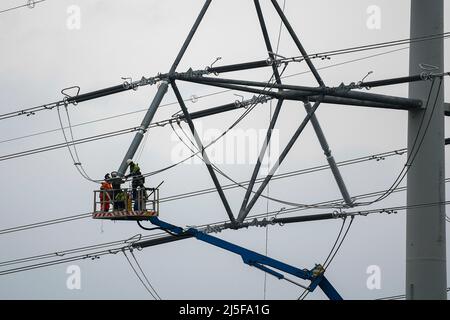 Bridgwater, Somerset, UK.  23rd April 2022.  Workmen on an aerial platform working on one of the new National Grid T-Pylons at Bridgwater in Somerset which have been built across the Somerset levels as part of the Hinkley Point C.  Picture Credit: Graham Hunt/Alamy Live News Stock Photo