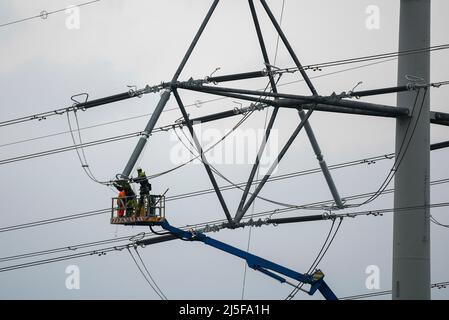 Bridgwater, Somerset, UK.  23rd April 2022.  Workmen on an aerial platform working on one of the new National Grid T-Pylons at Bridgwater in Somerset which have been built across the Somerset levels as part of the Hinkley Point C.  Picture Credit: Graham Hunt/Alamy Live News Stock Photo