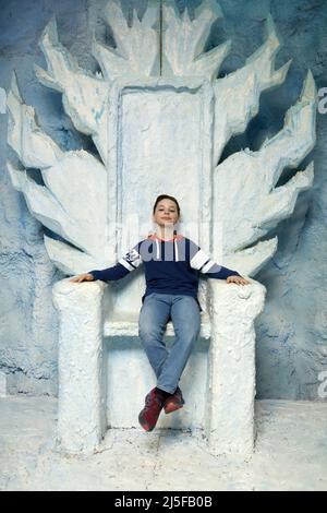 Portrait of child sitting on blue throne Stock Photo