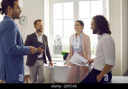 Colleagues discuss new business program, have fun and enjoy friendly conversations in office. Stock Photo