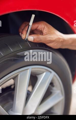 Close-Up Of Man Checking Tread On Car Tyre With Gauge Stock Photo