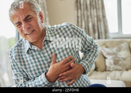 Mature Man Clutching Chest And Suffering Heart Attack At Home Stock Photo