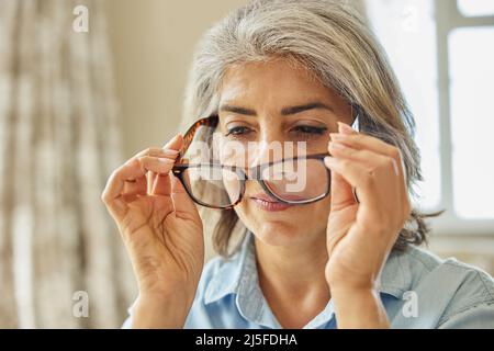 Smiling Mature Woman Trying On New Glasses At Home Stock Photo