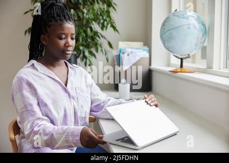 Unhappy Teenage Girl Closing Lid Of Laptop Computer After Online Abuse And Bullying On Social Media Stock Photo