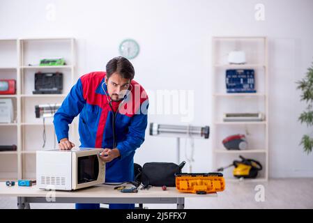 Young repairman repairing oven at workshop Stock Photo