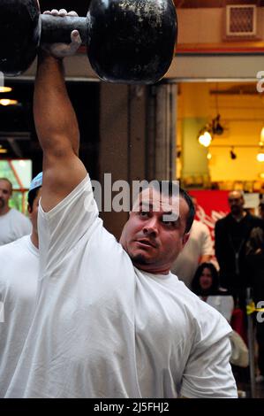 A  competitor lifts a dumbell over his head in a Strongman Competition, Eau Claire Market, Calgary, Alberta Stock Photo