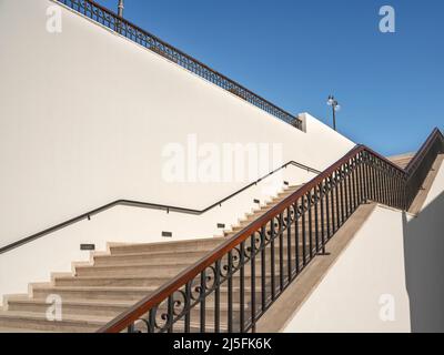 Wide staircase uphill with stone steps along a light wall. Career growth concept. Stock Photo