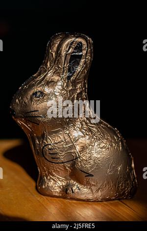 Easter bunny, in golden wrapping, standing sideways. Stock Photo