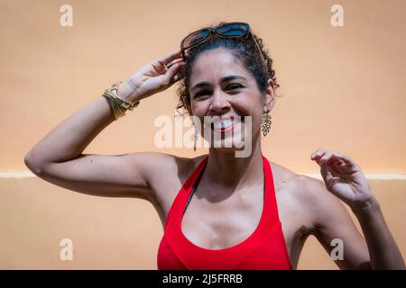 Close-up of a woman against orange background on the street. Salvador, Bahia, Brazil. Stock Photo