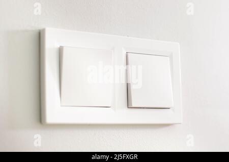 Light switches, white plastic mechanical switches mounted on white walls. Stock Photo