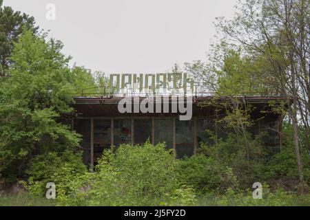 Pripyat, Ukraine - May 11, 2019: View of the facade of the abandoned building of the Pripyat cafe. The sign on the eaves of the roof Pripyat is the na Stock Photo
