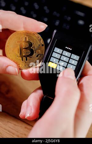 Close up womans hand holding bitcoin and cryptocurrencey hardware cold wallet on keybord background. Secure cryptocurrency storage. Stock Photo
