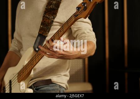 The guy plays the bass guitar. Bass guitarist holds an electric guitar in his hands and plays on it Stock Photo