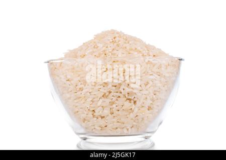 Uncooked organic rice in a glass bowl, macro, isolated on a white background. Stock Photo