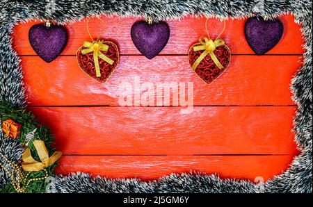 Christmas composition on red wooden board with Christmas garland and decorations. Creative composition with border and copy space, top view, flat lay. Stock Photo
