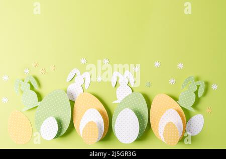 The concept of the Easter background. Decorative paper eggs and creative handmade rabbits on a green background, selective focus Stock Photo