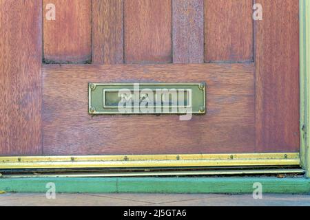 Letterbox on a wooden door at San Francisco, California. Metal letterbox with mail at the front at the bottom of the wooden door near the gold nailed Stock Photo