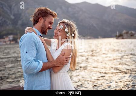 Newlywed couple in love by seaside. Romantic date of bride and groom, hugging. Wedding, honeymoon, love concept Stock Photo