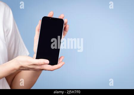 Woman holding cell phone in her hand and showing smartphone screen direct to camera. Front view Stock Photo