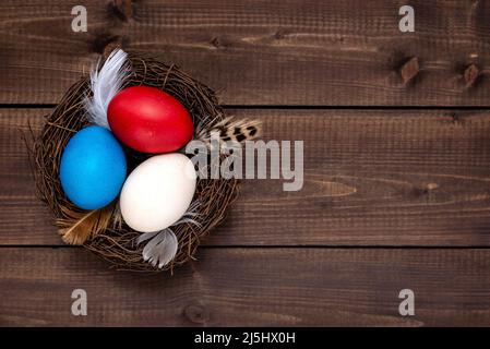 Multicolor decorated Easter eggs in the nest on a rustic wooden table. Easter concept. Stock Photo
