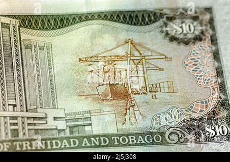 Detail of a ten dollar banknote from Trinidad and Tobago showing a container terminal with a ship being loaded using large cranes.  Used banknote phot Stock Photo