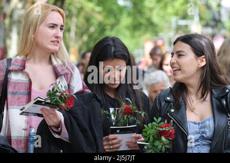 Barcelona, Spain. 23rd Apr, 2022. People holding roses walk on the street in Barcelona, Spain, April 23, 2022. St. George's Day usually sees the streets of Barcelona filled with parades of people exchanging books and flowers with their loved ones. Credit: Meng Dingbo/Xinhua/Alamy Live News Stock Photo