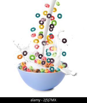 Pouring of tasty corn rings and milk into bowl on white background Stock Photo