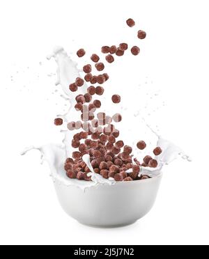 Pouring of tasty chocolate corn balls into bowl with milk splashes on white background Stock Photo
