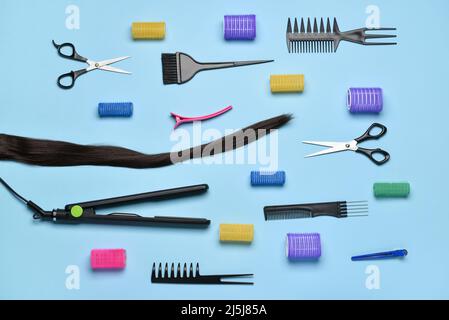 Composition with hair strand, hairdresser's tools and curlers on blue background Stock Photo